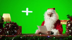 Santa sitting against isolated copy space screen and reading letters from kids around the world. Old man Saint Nick spreading his festive spirit for the Christmas holiday period. Camera B. - Powered by Shutterstock - Get 15% off with code: PIKWIZARD15