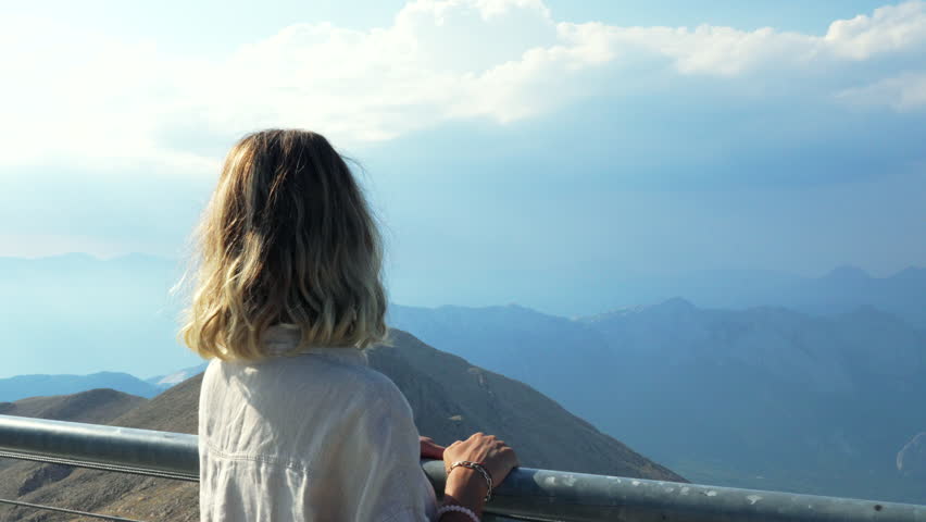 The woman is looking at the mountains