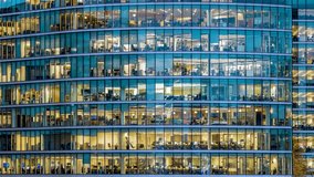 Timelapse panning view of an illuminated office building during evening with workers movement - Powered by Shutterstock - Get 15% off with code: PIKWIZARD15