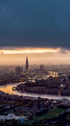 Moody sunset to night time lapse view of the London skyline with sun, clouds and rain showers