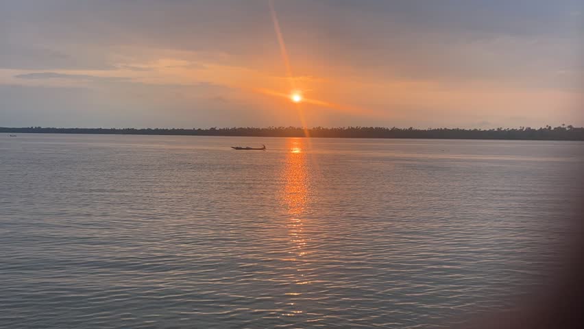 A drone timelapse of a boat crosses the river with a sunset scene background in Calabar, Nigeria