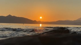 A timelapse of sunrise scene on a rocky shore with silhouetted mountain in the background, a boat crossed the view - Powered by Shutterstock - Get 15% off with code: PIKWIZARD15