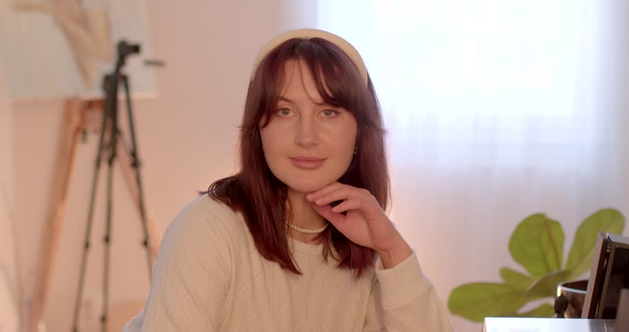 A stylish and fashionable woman is smiling brightly in a warm, inviting space that radiates elegance and confidence