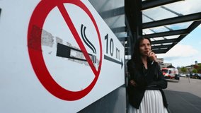 A woman near a no smoking sign, indicating compliance with health and safety rules - Powered by Shutterstock - Get 15% off with code: PIKWIZARD15