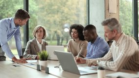 Diverse team of business professionals collaborating on project in modern office, using laptops and documents - Powered by Shutterstock - Get 15% off with code: PIKWIZARD15