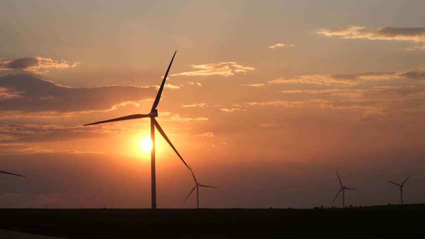 Wind turbines at sunset. Wind turbines in the orange sky. Rural areas with renewable energy sources. The concept of environmental safety green energy. Landscape with windmills. Sustainable development