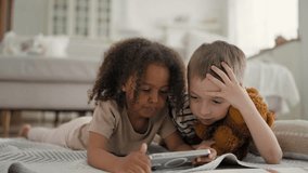 Little African girl and Caucasian boy watching educational video in mobile app. Multiracial children in kindergarten, spending time online, using smartphone with internet connection, modern technology - Powered by Shutterstock - Get 15% off with code: PIKWIZARD15
