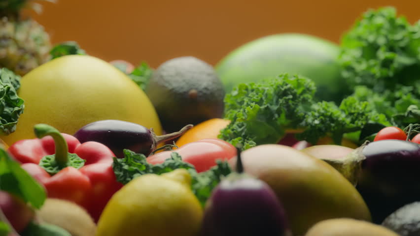 Close up of assortment of fruits and vegetables on orange background. Nutrition and healthy diet concept.