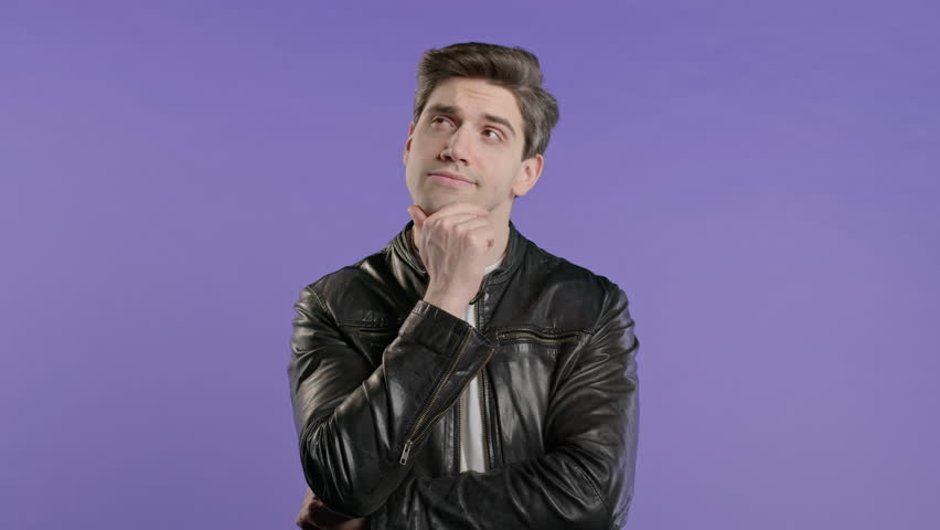 Portrait of curious analyzing man in violet studio. Mindful guy finding solution