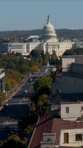 Vertical Video Aerial view of Washington DC with a street lined with trees and buildings, including the US Capitol in the distance.
