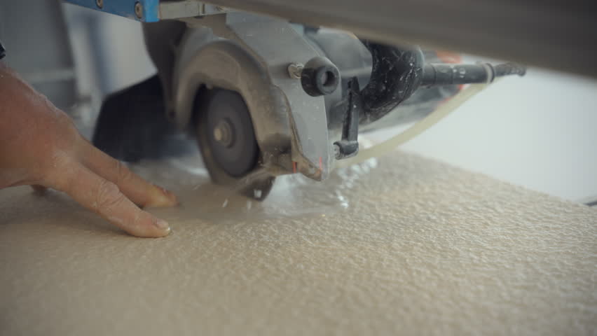 Close up view of Cutting machine with water-cooled and circular saw cuts piece of tile. 