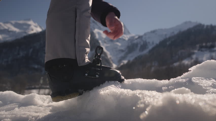 Skier puts his foot with ski shoes on the snow, fastens the fastening. Adjusting boot buckle on ski boot. Ski resort or a slope. Preparation for skiing. Winter sport and holiday. Big. 3D Illustration