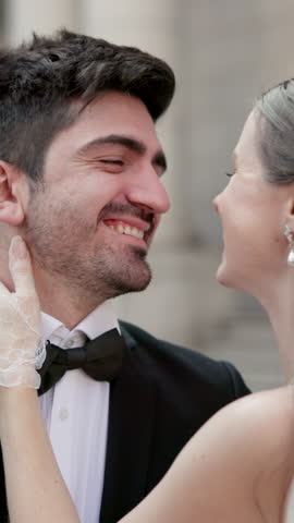 Kiss, happy and couple in city for wedding with love, connection and care for commitment event. Smile, bonding and young bride and groom with romance for marriage ceremony outdoor in town together.