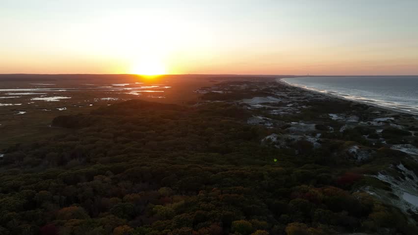 The great Salt Marsh and sand dunes at Cape Cod, during an orange sunset.