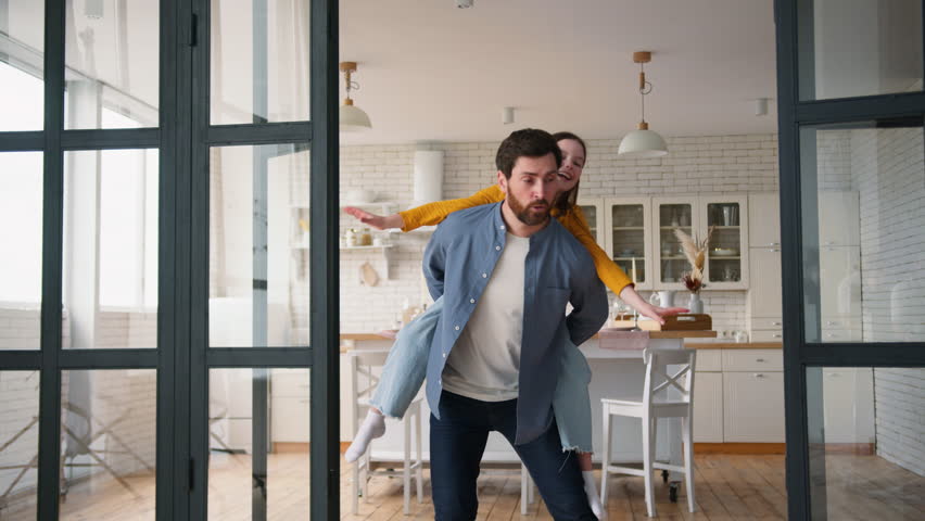 Smiling Caucasian daughter dad male daddy having fun guy girl dancing together enjoying weekend playing at home little kid piggyback ride happy father man carry child family laughing leisure childcare