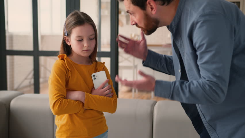 Irritated Caucasian father man parent scolding talk guilty device addicted little child girl daughter kid family problem quarrel offend. Angry dad male take away mobile phone punishment argument home