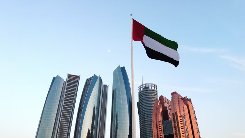 UAE flag in front of modern high rise buildings in Abu Dhabi. High quality 4k footage.