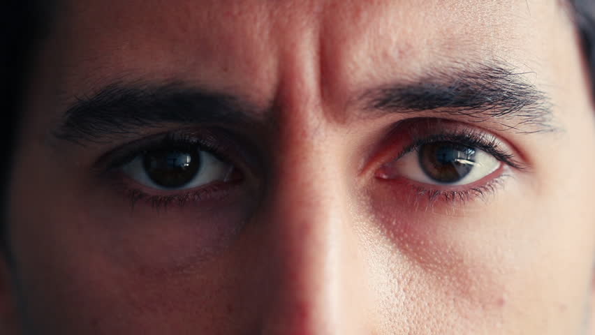 Man opens his eyes in a close-up, showing a relaxed and calm expression. His gaze is gentle, conveying a sense of composure and mindfulness, capturing a moment of quiet reflection