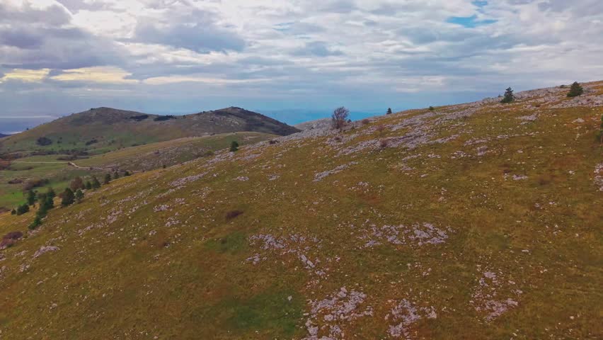 Croatia. Calm autumn mountain landscape. The drone slowly rises above the green hills of the mountains, gradually revealing a view of the Adriatic Sea 