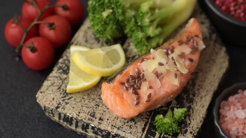 Grilled salmon with salt and spices, broccoli, tomatoes, rice on a dark concrete background
