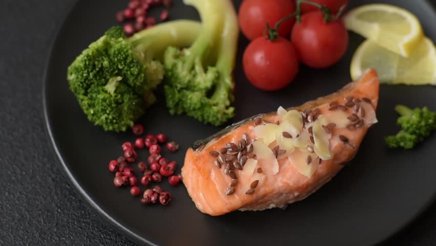 Grilled salmon with salt and spices, broccoli, tomatoes, rice on a dark concrete background