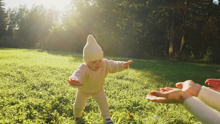 baby falls into the grass learns to walk in the park. happy family kid dream concept. baby takes the first steps unsuccessfully falls in nature