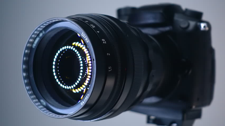 A professional camera on a tripod with an expensive lens with an aperture of 1.5 and a focal length of 85 mm, which reflects the ring LED light. Closeup. Macro