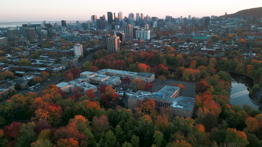 aerial shot going backward tilting up revealing Montreal city skyline from Lafontaine Park at sunset during fall season, Quebec Province, Canada