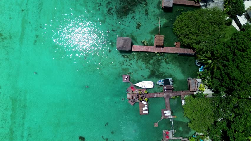 Drone aerial landscape of boats docked by wharf jetty in Bacalar lagoon lake sandbar resort huts restaurants Quintana Roo Mexico travel vacation tourism holidays