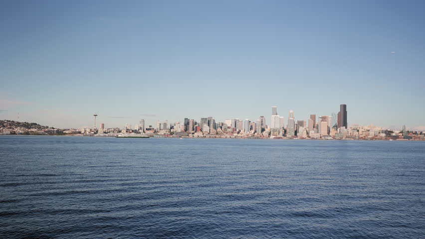 A wide view of the Seattle, Washington skyline as seen across the Elliott Bay. A ferry crosses frame