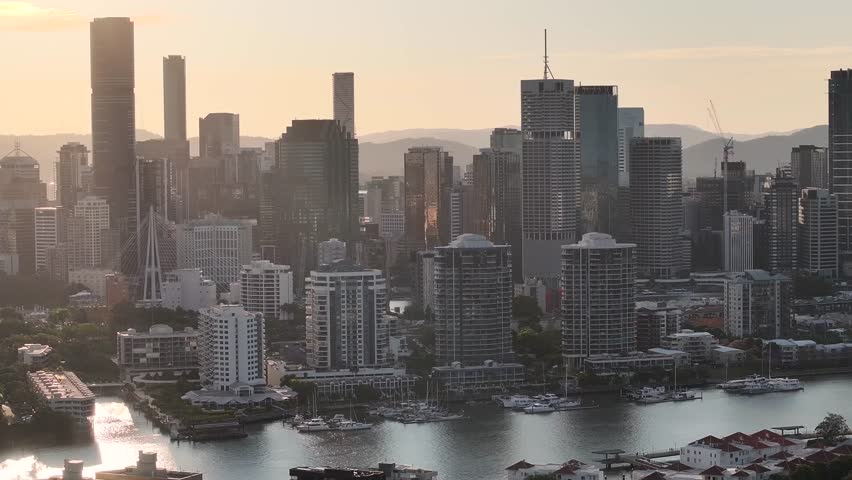 Metropolitan area of Brisbane city centre with tall buildings during warm sunset. Drone aerial
