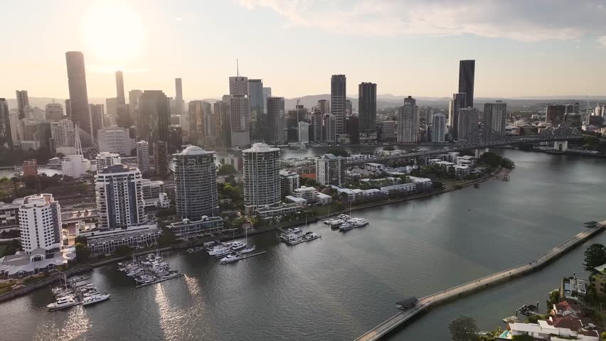 Brisbane, Australia. Drone pull back over the river, residential area with promenade in the evening.