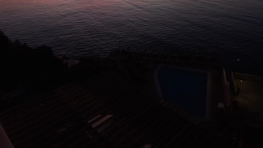 Golden red sunset over Bay of Palma, capturing the serene horizon with the silhouette of trees, creating a tranquil and picturesque coastal scene. tilt up shot