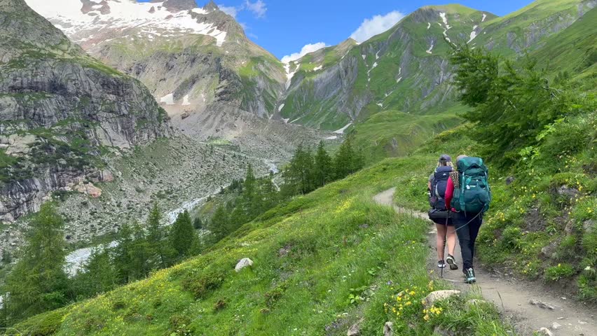 a pair of people hiking in the ALPS mountains - following the TMB (Tour du Mont Blanc) trail