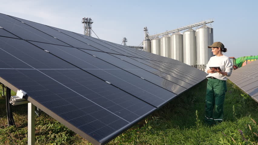 Female farmer with digital tablet on a modern farm using solar panels. Agricultural silos in the background - Powered by Shutterstock - Get 15% off with code: PIKWIZARD15