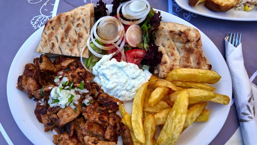 Chicken gyros plate, typical Greek food tzatziki chips salad pita bread