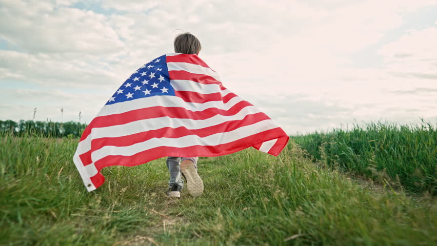 Cute little boy - American patriot kid running with national flag on open area countryside road.USA, 4th of July - Independence day, celebration. US banner, memorial Veterans, election