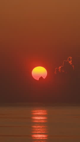Timelapse of dramatic sunrise with orange sky in a cloudy day at the ocean.
