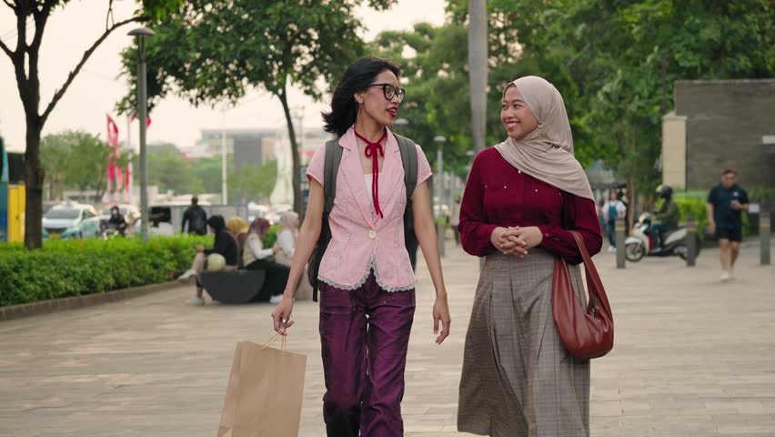 Young Modern Asian girl friends walking and enjoying conversation in the city. Diversity and friendship in Indonesia