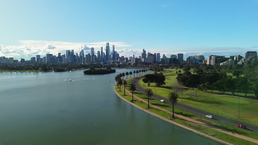 Cinematic flight over Albert Park Lake with Melbourne city skyline in the background