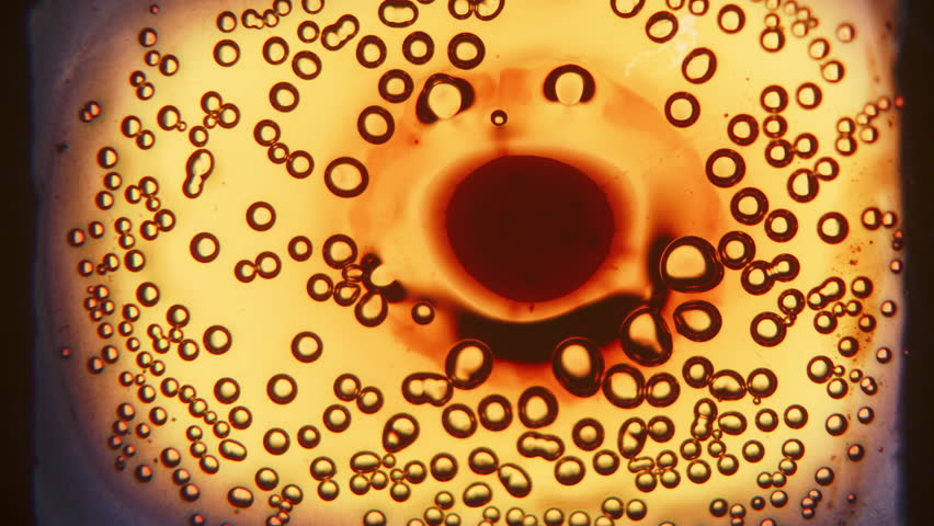 A mesmerizing close-up of tiny yellow bubbles forming and rising on vintage film as it burns, creating a striking interplay of light and texture