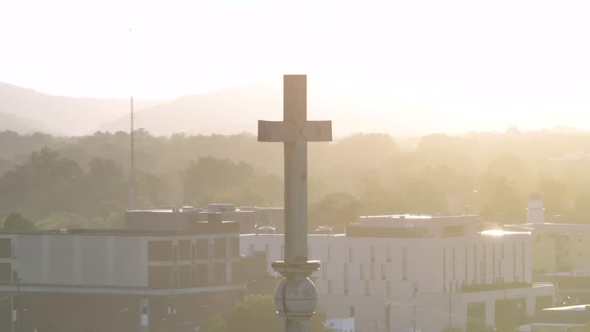 Aerial close up of cross on top of church tower during foggy day. American town in autumn season. Orbit shot. Sunset time in America.