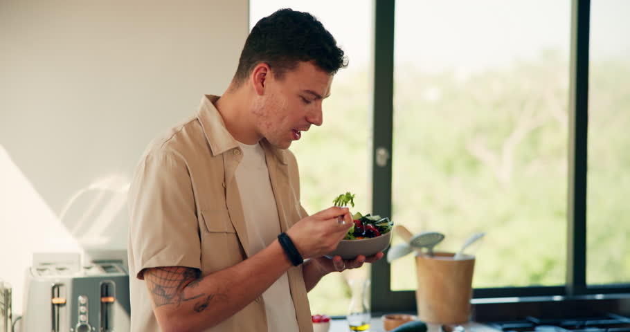 Salad, bowl and man with eating in kitchen for nutrition, healthy diet and vegetarian meal with enjoyment. Person, wellness and organic brunch in home with satisfaction, hungry and delicious food