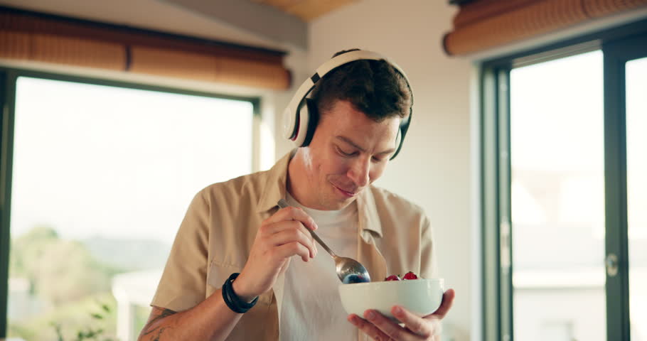Happy man, headphones and dancing with salad bowl for music, breakfast or healthy meal at home. Young, male person or nutritionist feeling good with snack and organic food for morning in kitchen