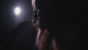 Close-up of the face of the singer with microphone on a black smoky background. The singer sings a song on stage in the dark, smoke, purple light, concert. - Powered by Shutterstock - Get 15% off with code: PIKWIZARD15