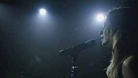 Close-up of the face of the singer with microphone on a black smoky background. The singer sings a song on stage in the dark, smoke, purple light, concert. - Powered by Shutterstock - Get 15% off with code: PIKWIZARD15