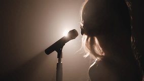 Close-up of the face of the singer with microphone on a black smoky background. The singer sings a song on stage in the dark, smoke, purple light, concert. - Powered by Shutterstock - Get 15% off with code: PIKWIZARD15