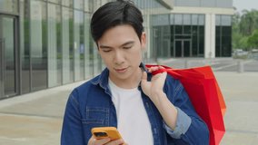Young man holding a shopping bag and using phone on the street - Powered by Shutterstock - Get 15% off with code: PIKWIZARD15