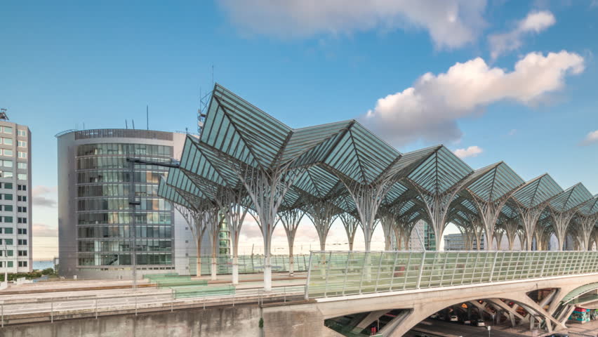 Lisbon Oriente Train and Bus Station aerial timelapse where steel and glass trees interlock to form a continuous system of transparent roofs. Panorama during sunset with clouds. Lisbon, Portugal