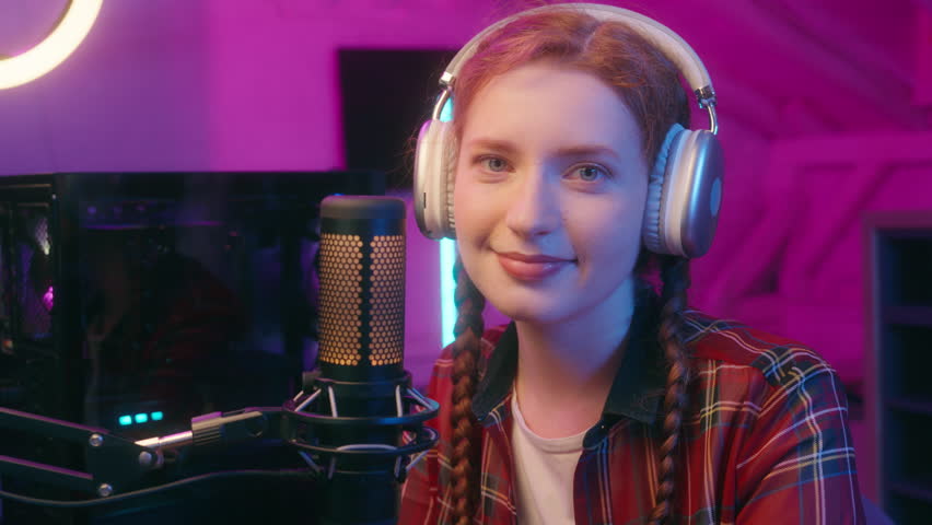 Caucasian woman teenager girl student female streamer blog cyber sport gaming addiction influencer blogger vlogger computer video game radio stream mic broadcast looking at camera smiling neon light